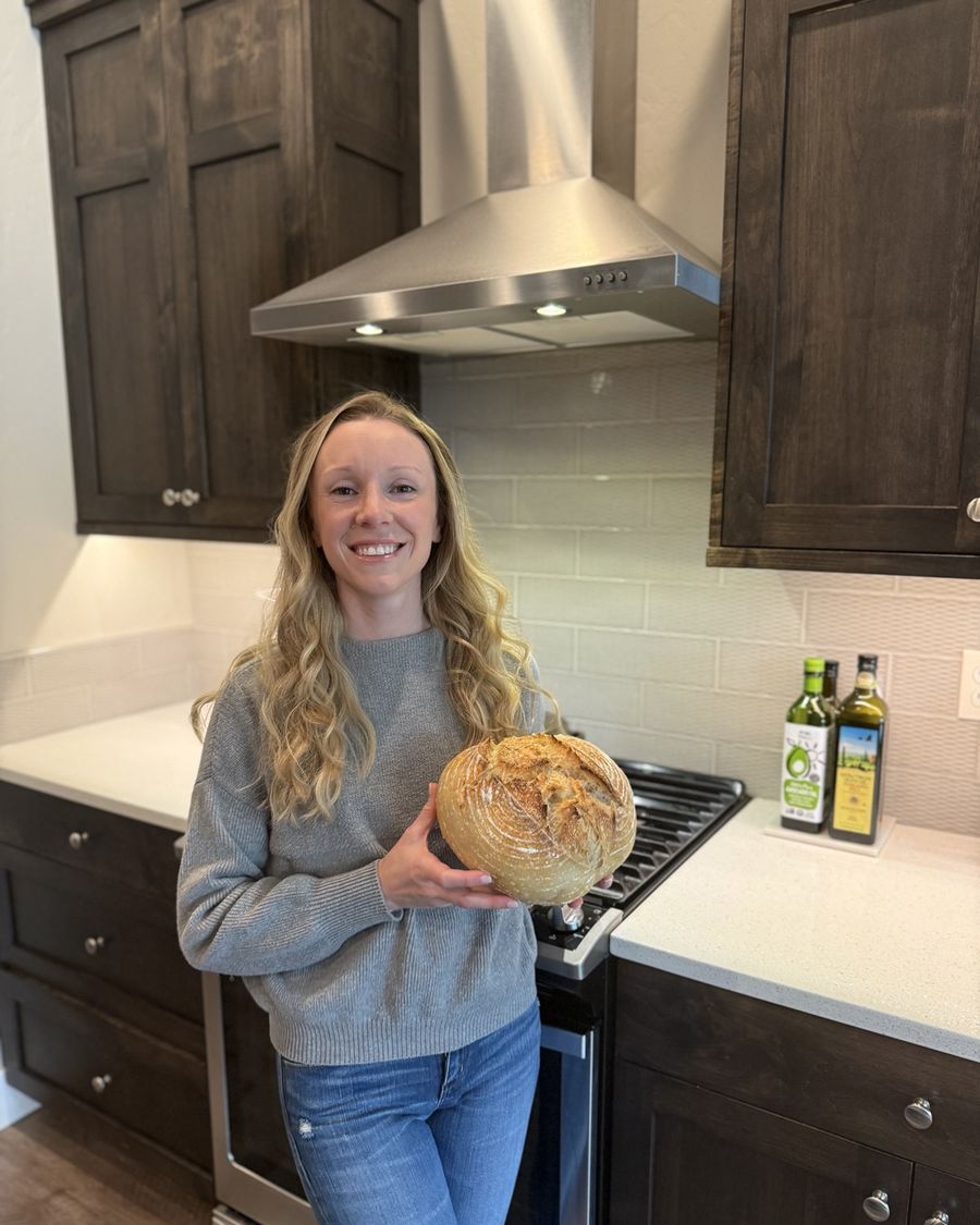 Victoria holding a fresh sourdough loaf in her kitchen